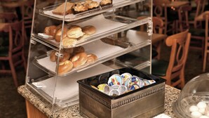 A buffet setup with multiple trays of baked goods and a container of beverages.