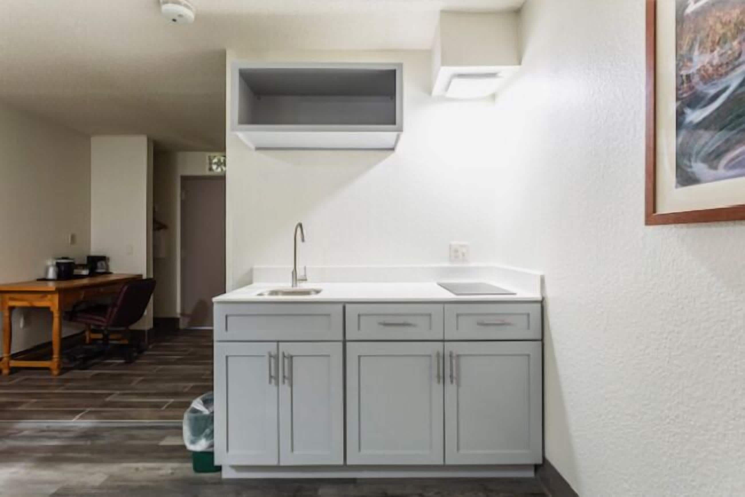 A compact kitchen with a sink, cabinets, and a small window above the counter.