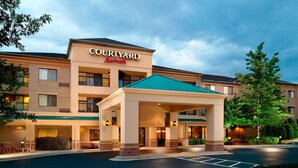 Ein Courtyard Marriott Hotel mit überdachter Einfahrt, mehreren Stockwerken und einem Parkplatz.