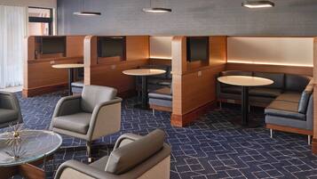 A modern hotel lobby with seating areas, tables, and a patterned carpet.