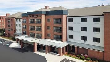 A multi-story hotel with a brick facade, named "COURTYARD," featuring a covered entrance and multiple balconies.