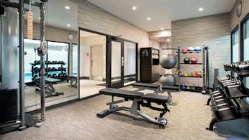 Une salle de sport moderne équipée de matériel de musculation, de ballons d’exercice et d’haltères.