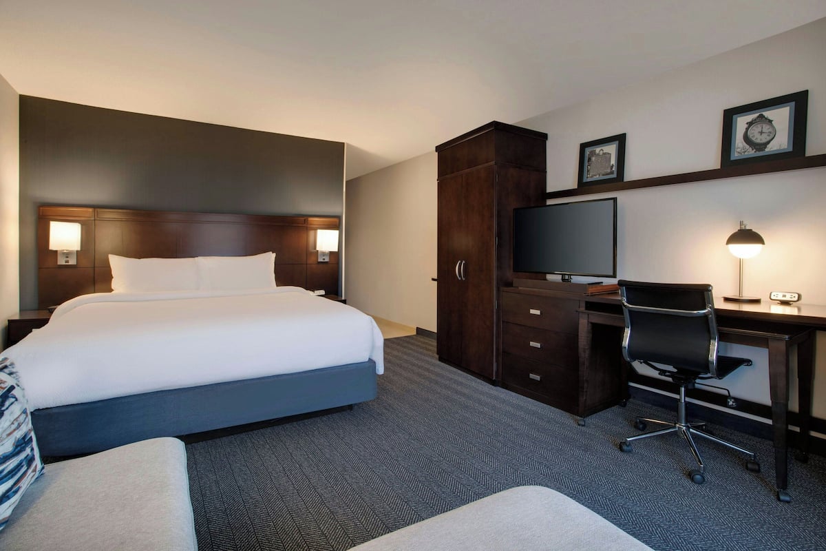 Een hotelkamer met een groot bed, een bureau met een computer, een stoel en een televisie.
