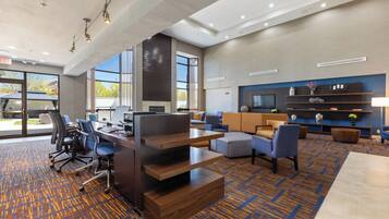 Un moderno vestíbulo de hotel con un mostrador de recepción, zona de estar y amplios ventanales con vistas al exterior.
