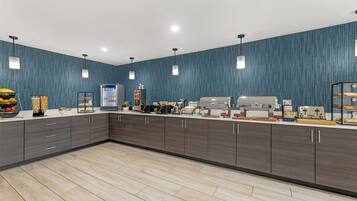 A modern kitchen with dark wood cabinets, a white countertop, and a blue textured wall.