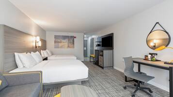 A hotel room with a bed, a desk, a chair, a TV, and a mirror.