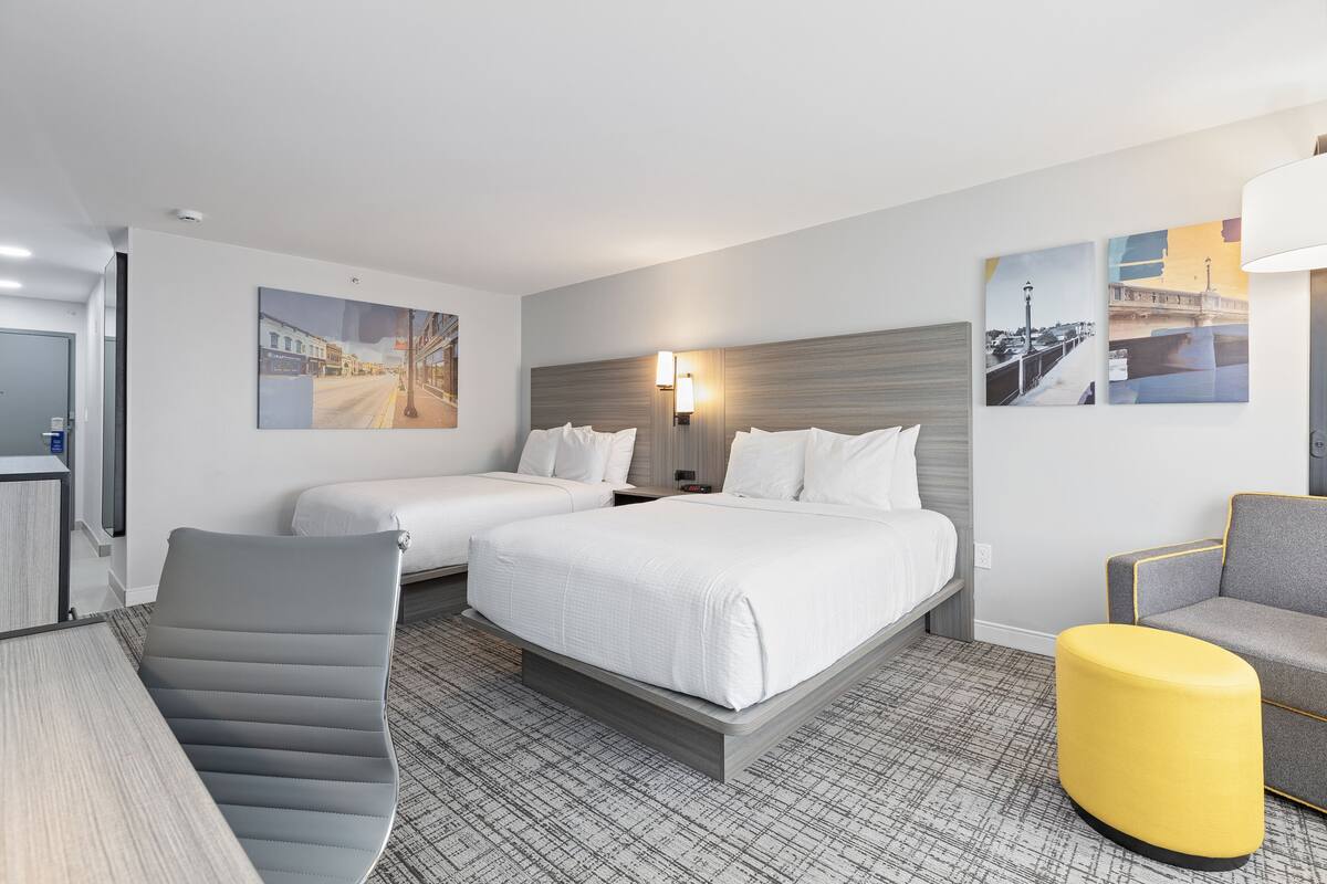 Una habitación de hotel con una cama, dos mesitas de noche, un escritorio, una silla y un sofá.