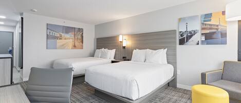 Una habitación de hotel con una cama, dos mesitas de noche, un escritorio, una silla y un sofá.