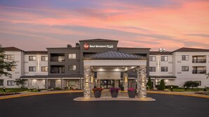 Ein Best Western PLUS Hotel mit modernem Design, das einen zentralen Eingangsbereich mit einer überdachten Durchgang und Steinsäulen sowie Pflanzkübeln zeigt.