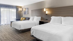 Ein Hotelzimmer mit zwei Betten, einem großen Fenster mit durchsichtigen Vorhängen, einer Wandlampe und einem Gemälde.