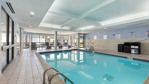 Ein Swimmingpool mit Fliesenveranda, Liegestühlen und Blick ins Freie.
