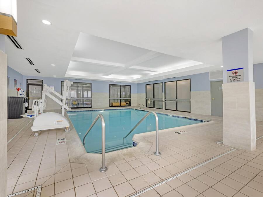 Una piscina cubierta con zona transparente, una silla de socorrista y un letrero que indica que no se permite comer ni beber.