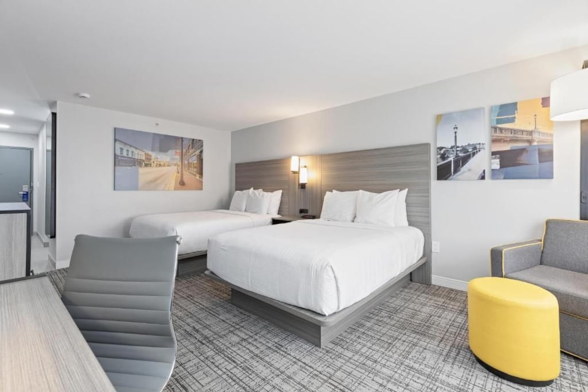 Ein Hotelzimmer mit zwei Betten, einem Schreibtisch, einem Stuhl und Bildern an den Wänden.