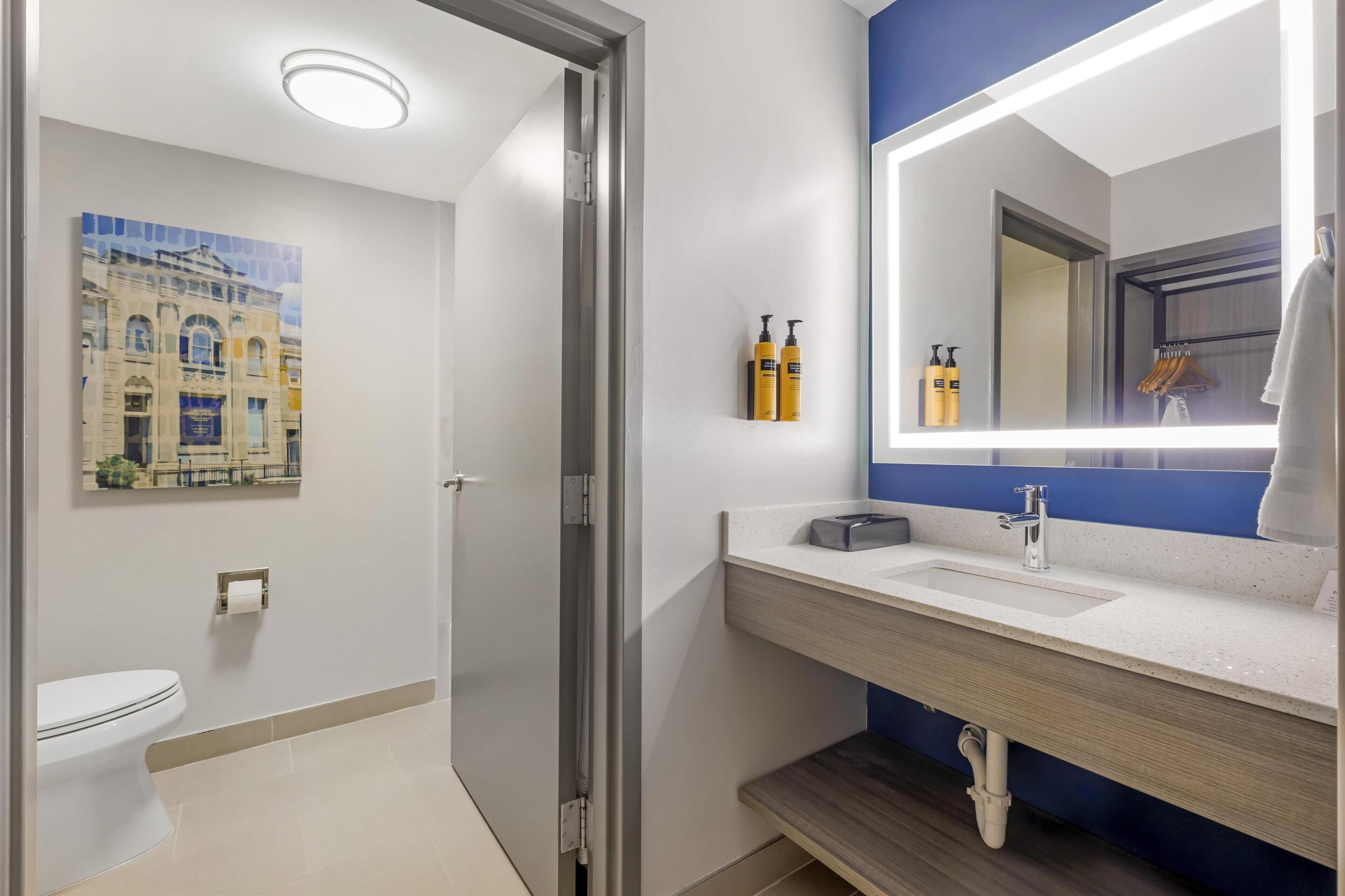 Un bagno moderno con un WC bianco, un lavabo con specchio e una parete azzurra.