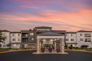 Een Best Western PLUS hotel met een modern design, met een centrale ingang voorzien van een overdekte doorgang, stenen pilaren en plantenbakken.