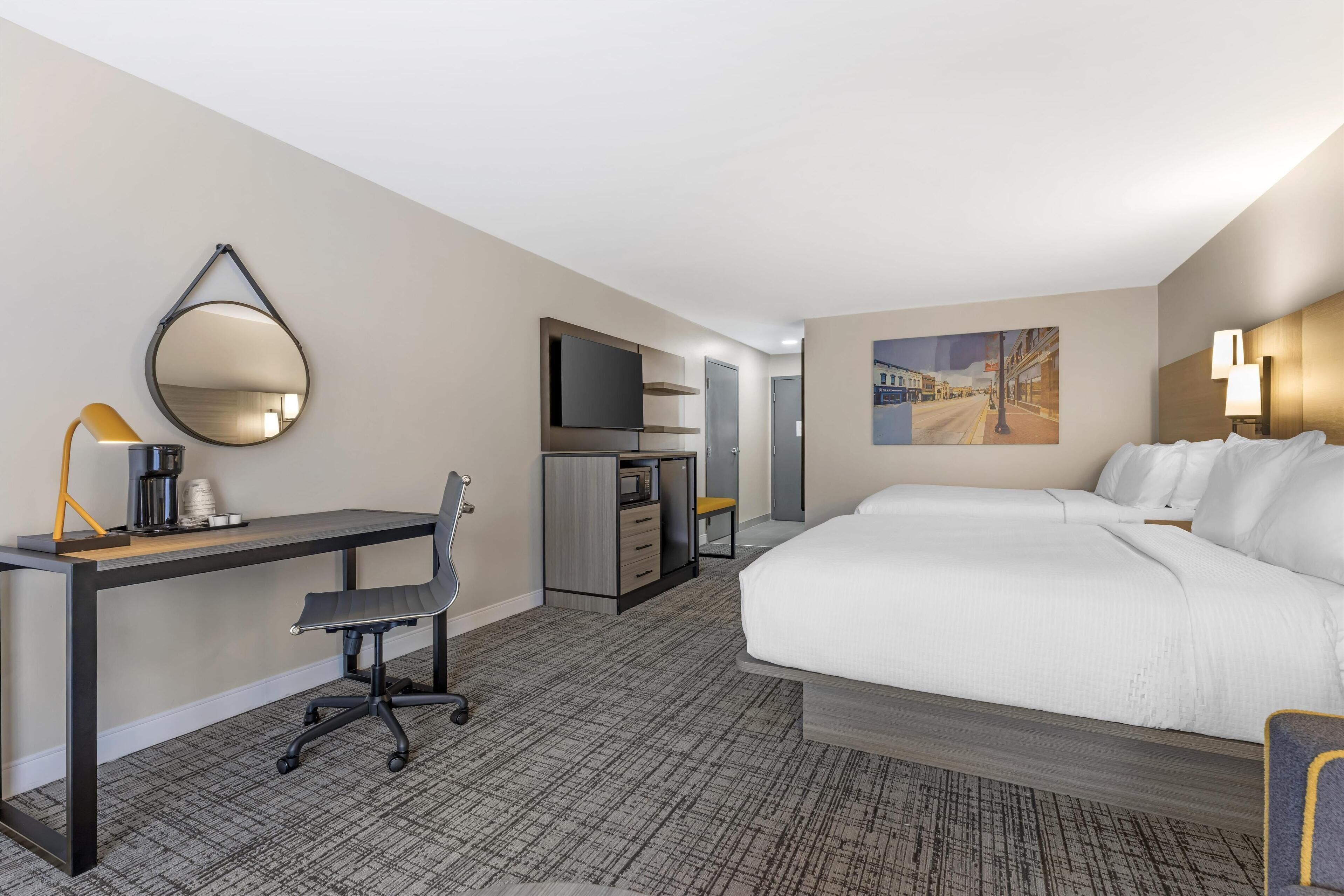 A hotel room with a bed, desk, chair, and a TV.