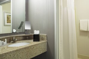 A bathroom with a granite sink, a mirror, a towel rack, and a shower curtain.
