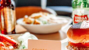 A table with a burger, a plate of food, and two bottles of beverages. A sign with the text "COURTYARD BY MARRIOTT" is in the foreground.
