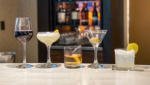A bar area with various glasses of drinks and a shelf of bottles in the background. - Courtyard Chicago St. Charles (St. Charles)