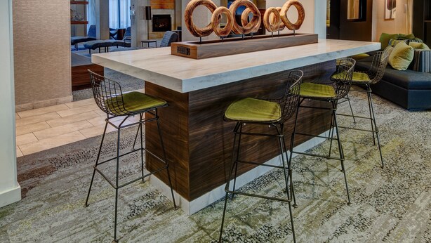 A modern bar area with a wooden counter and metal bar stools. - Courtyard Chicago St. Charles (St. Charles)