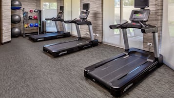 A fitness room with treadmills, exercise balls, and a weight rack.