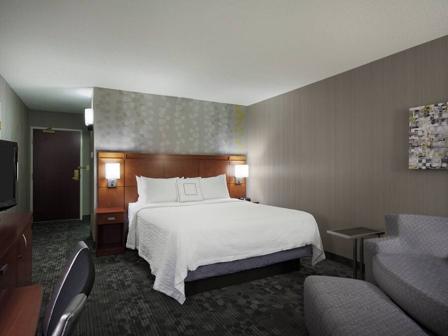 A hotel room with a bed, a TV, a desk, a chair, and a sofa.