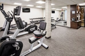 A gym with treadmills, weight machines, and dumbbells.