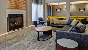 A modern living room with a fireplace, a sofa set, and a round coffee table. - Courtyard Chicago St. Charles (St. Charles)