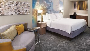 Une chambre d’hôtel avec un grand lit, un canapé, un bureau et une œuvre d’art murale.