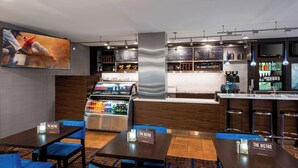 Un hall d'hôtel comprenant un bar, des sièges avec une signalétique indiquant «The Bistro», un grand écran de télévision et un présentoir réfrigéré.