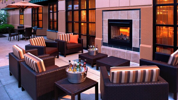 Une terrasse extérieure aménagée avec des meubles en osier, une cheminée et une table de billard.