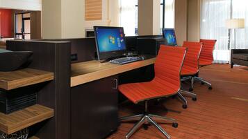 A hotel workspace with individual workstations, each equipped with a computer and a keyboard.