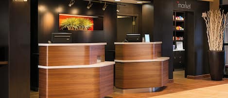 A reception desk with a modern design, a framed artwork above it, and a 'market' sign in the background.