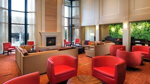 A spacious lobby with a fireplace, red seating, and a green wall feature.