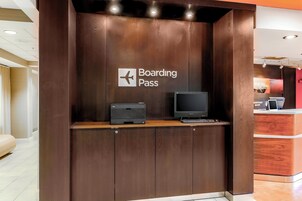 Um balcão de recepção de madeira com uma placa que diz 'Boarding Pass', uma impressora Dell e um monitor.