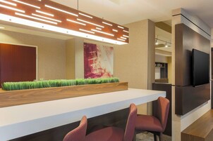 A modern kitchen with a long countertop, built-in seating, and a flat-screen TV mounted on the wall.