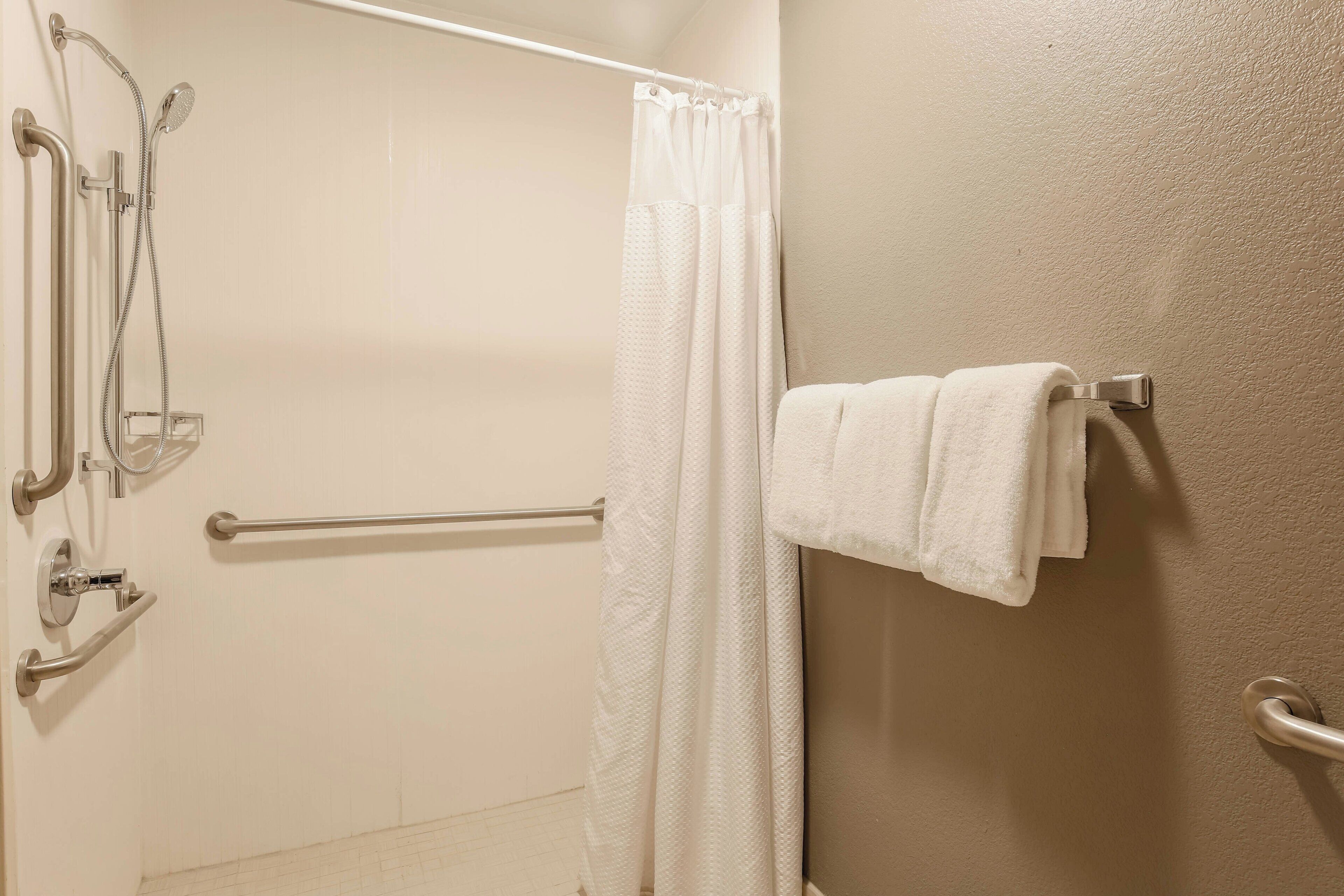 Une salle de bain équipée d’une douche, de barres d’appui et d’un porte-serviettes.