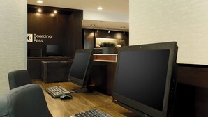 Un espacio de oficina moderno con un escritorio de madera, dos monitores de computadora, un teclado y una silla. Se ve un cartel que dice 'Boarding Pass' en la pared.