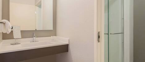 A bathroom with a white sink, a mirror, and a glass shower enclosure.