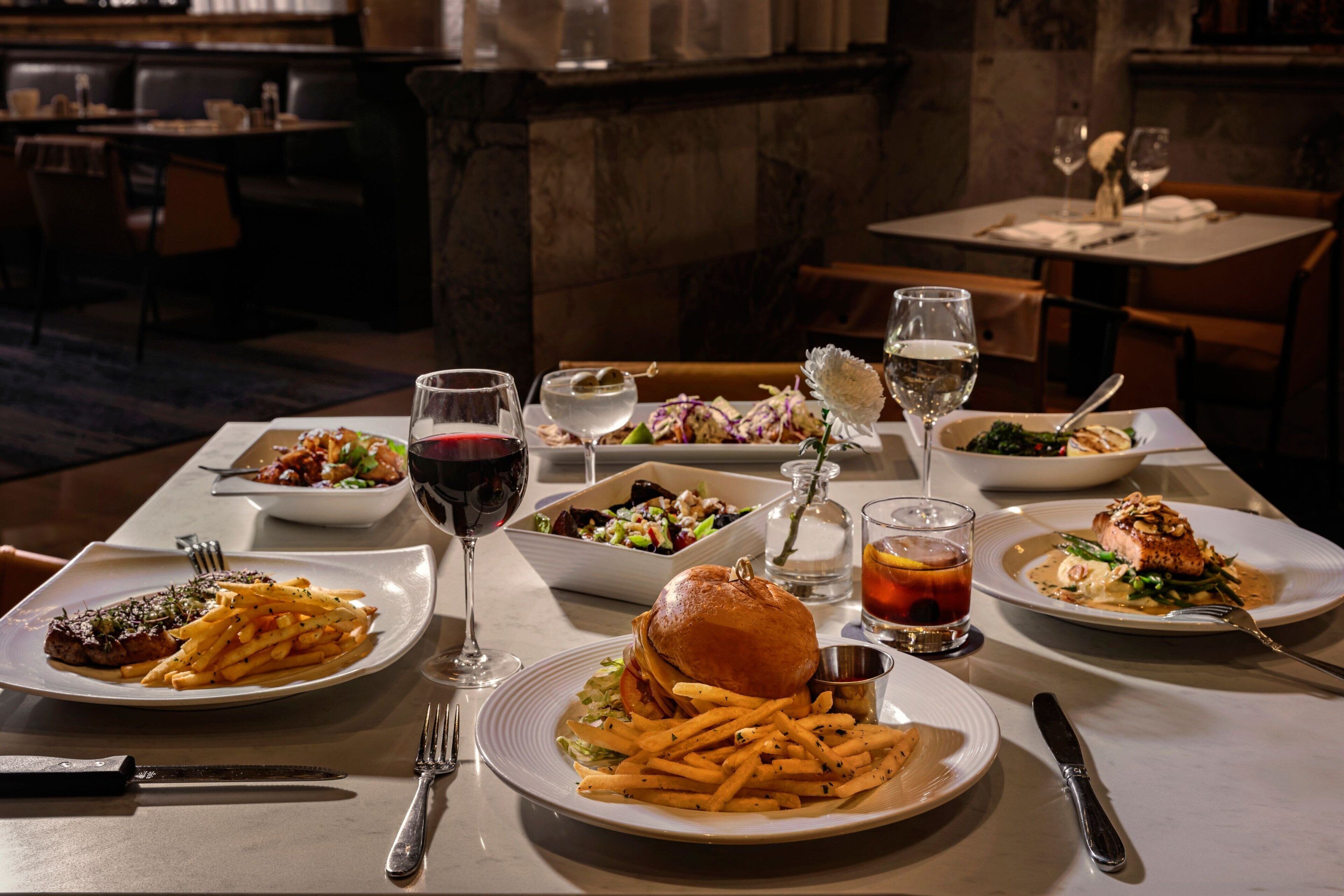 A dining table with various dishes, including steak, fries, and salads.