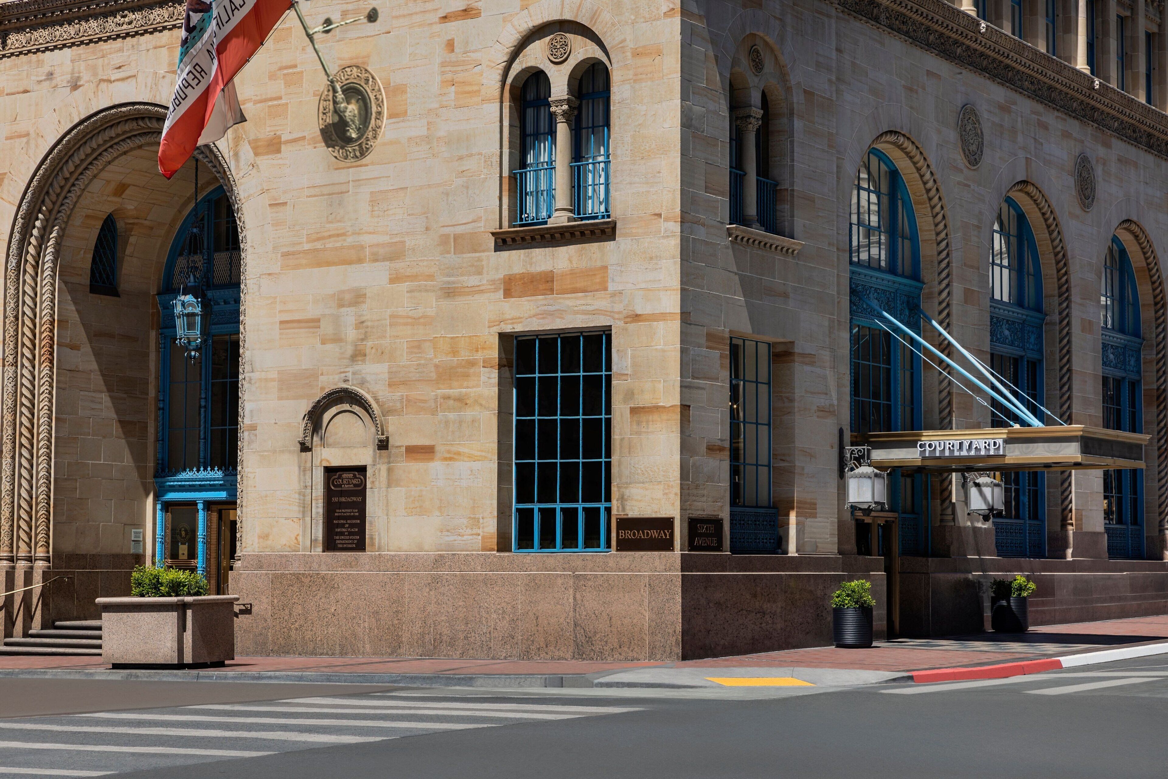 A historic building with arched windows, a sign reading "COURTLYARD," and a street-level entrance.