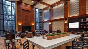 A modern hotel lobby with a fireplace, seating area, and a large screen displaying 'COURTYARD'. - Courtyard by Marriott Seattle Sea-Tac Area (Tukwila)