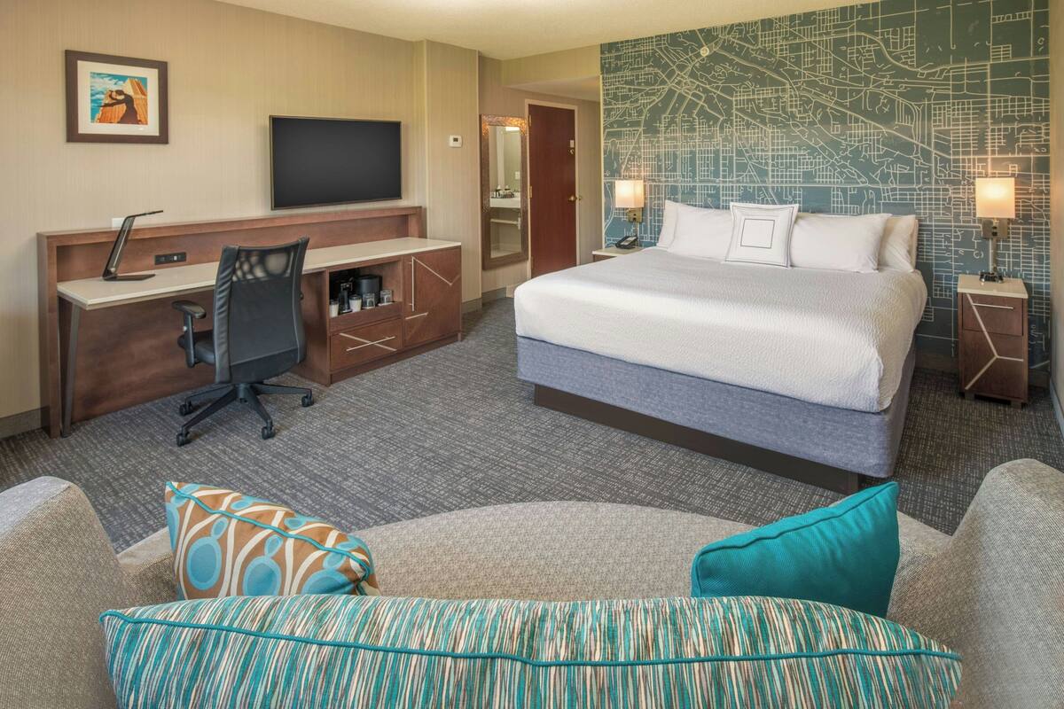 A hotel room with a bed, desk, chair, and a television.