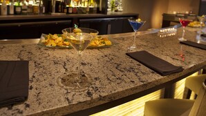 A bar area with a granite countertop, two martini glasses, and a bottle of liquor. - Courtyard by Marriott Seattle Sea-Tac Area (Tukwila)