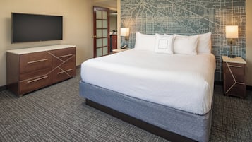 Habitación de hotel con una cama grande, un televisor de pantalla plana, un aparador de madera y un mural con motivos de mapa.