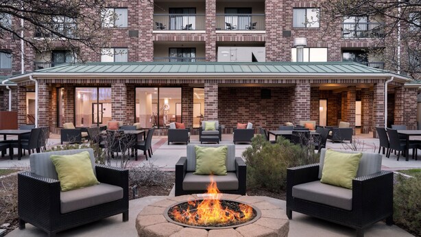 An outdoor patio area with a fire pit, seating, and a brick building in the background. - Courtyard by Marriott Salt Lake City Airport (Salt Lake City)