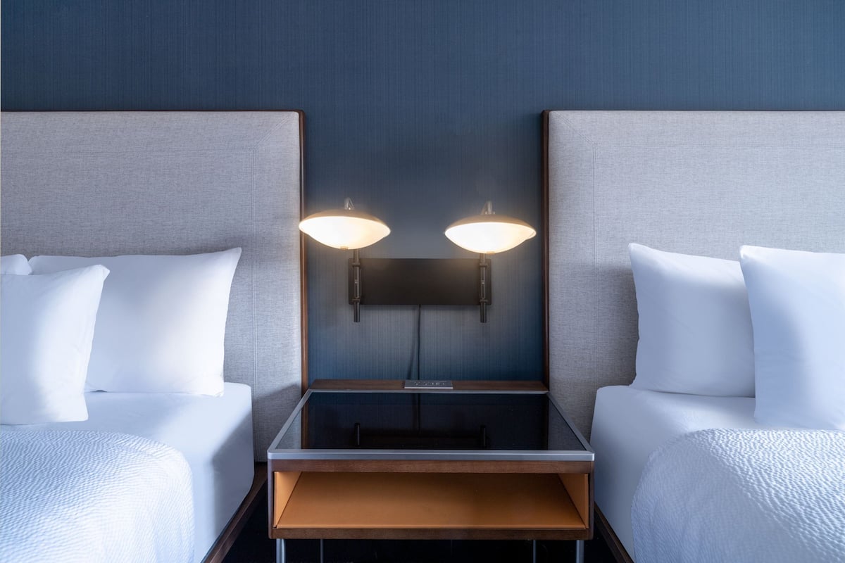Ein Hotelzimmer mit zwei Betten, einem Nachttisch und einer Wandleuchte.