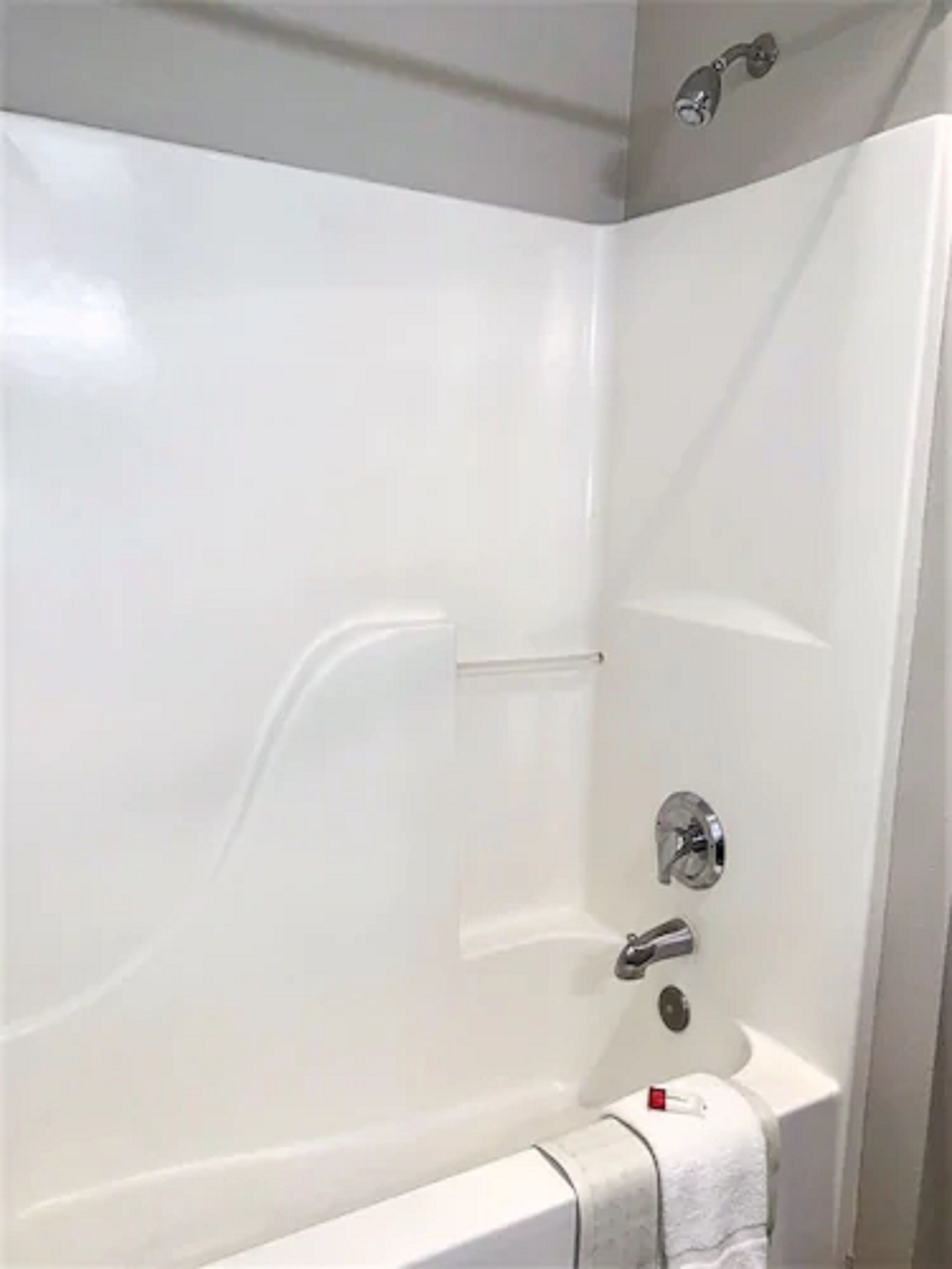 A modern bathroom with a white bathtub, a chrome faucet, and a towel rack.