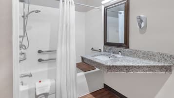 Un baño con ducha, lavabo, espejo y secador de pelo.