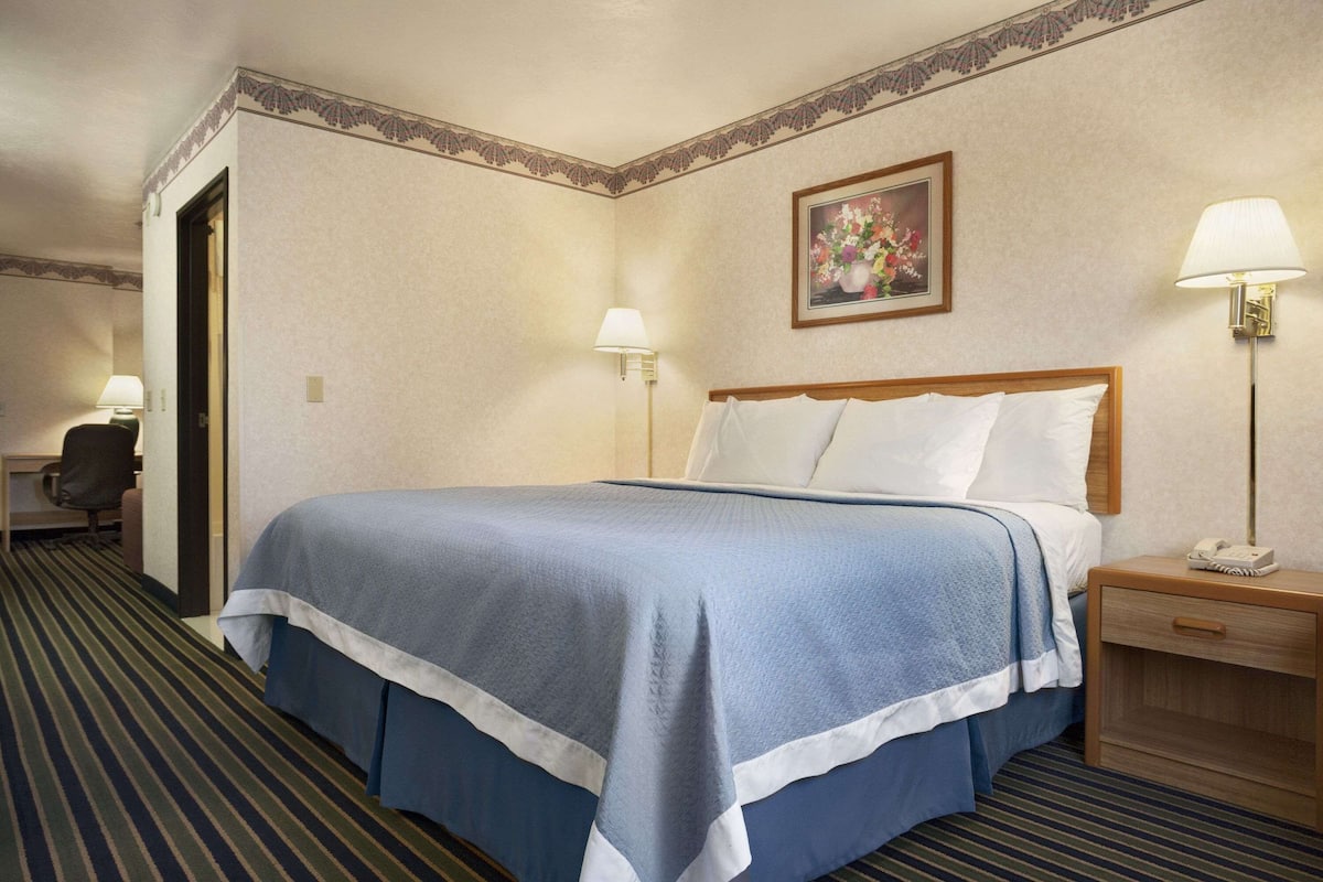 A hotel room with a bed, bedside tables, a desk, and a chair.